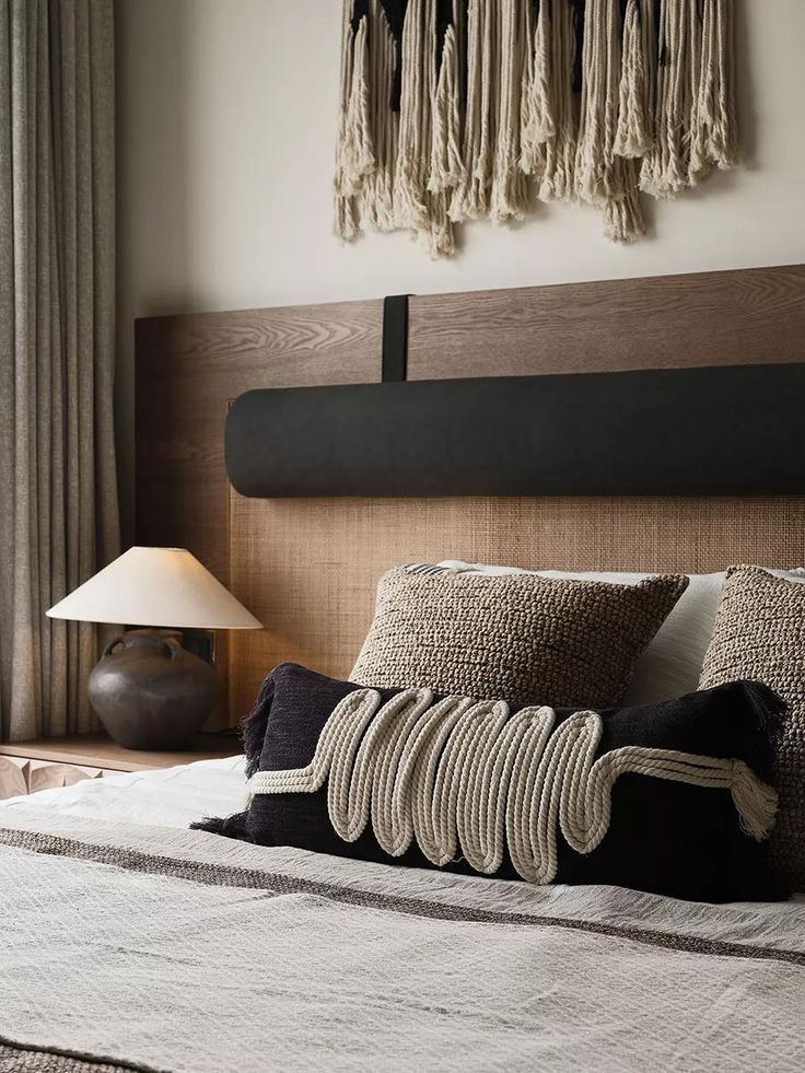 a bed with pillows and blankets on top of it next to a wall hanging above the headboard