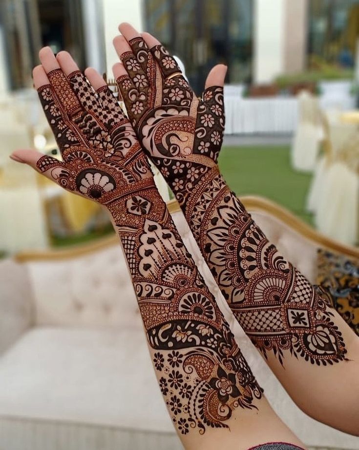 a woman's hands with hennap on it in front of a couch