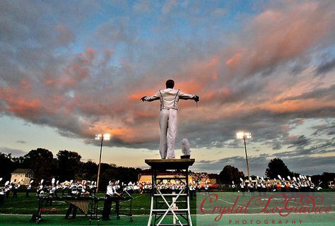 a man standing on top of a statue in the middle of a field at sunset