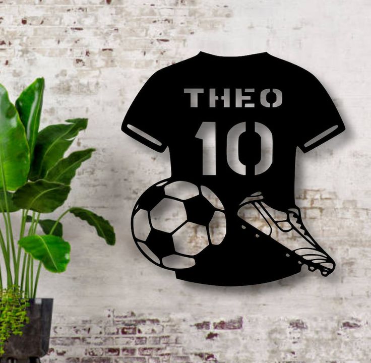 there is a soccer shirt and ball on the wall next to a potted plant