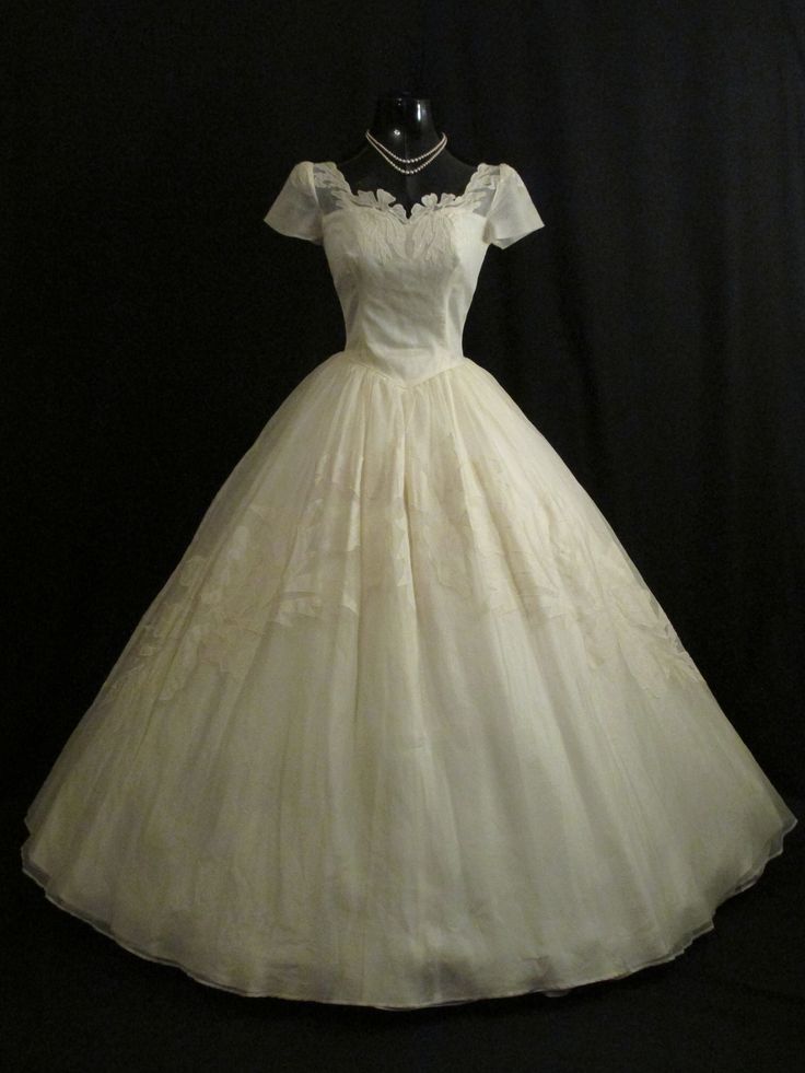 a white dress is on display in front of a black background with a mannequin