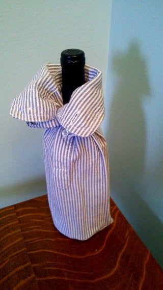 a wine bottle wrapped in a purple and white striped cloth with a black top sitting on a wooden table