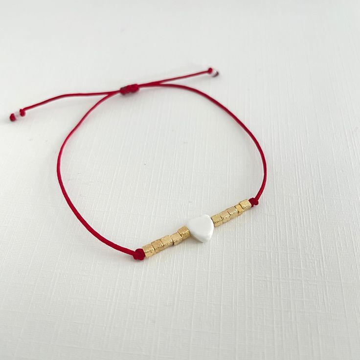 We sweeten this delicate bracelet with a mother-of-pearl heart surrounded by beads in a beautiful sparkling shade that radiates love. This bracelet is part of the JOSEMVALE affordable elegance. This bracelet is adjustable with a macramé knot to fit almost every wrist size. Mother of Pearl ~ 3 mic gold-plated or silver plated over brass ~ Red cotton cord ~ Avoid getting our jewelry wet. #JOSEMVALE Adjustable Heart-shaped Dainty Beaded Bracelets, Dainty Heart-shaped Adjustable Beaded Bracelets, Dainty Adjustable Heart Bracelets, Dainty Adjustable Heart Shaped Beaded Bracelets, Dainty Adjustable Beaded Heart Bracelet, Dainty Adjustable Heart-shaped Bracelet, Dainty Heart-shaped Adjustable Bracelets, Dainty Handmade Heart Friendship Bracelets, Elegant Adjustable Friendship Bracelets For Valentine's Day