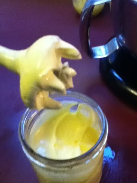 a banana peel is sticking out of a glass cup filled with yogurt on a purple table