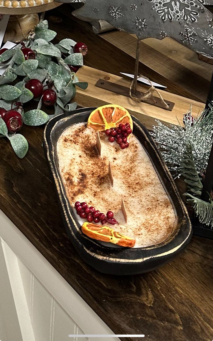 an old fashioned serving dish with fruit on it and christmas decorations in the back ground