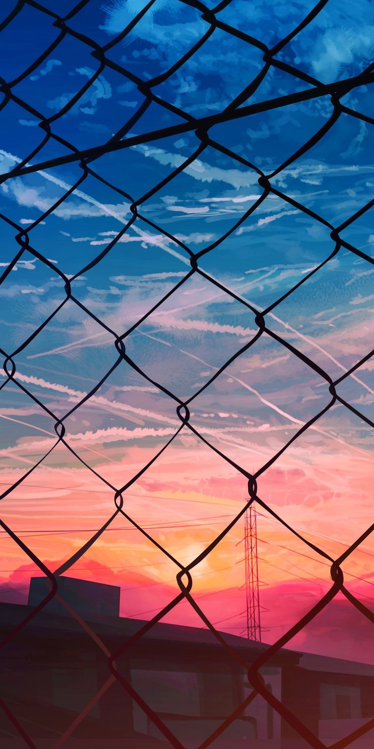 the sun is setting behind a chain link fence with an airplane in the sky above