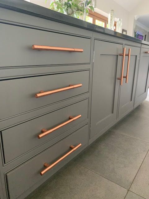 a kitchen with grey cabinets and copper handles