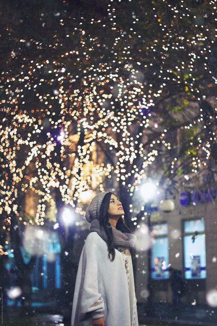 a woman standing in front of a tree covered in lights