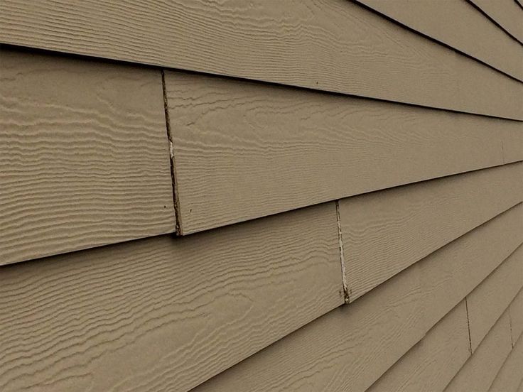 the side of a house that is tan with brown siding and woodgrains on it