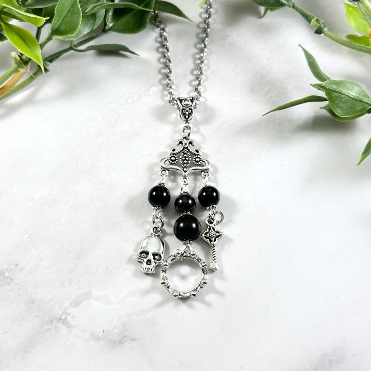 This beautiful chain necklace is the perfect way to express your affinity for the Greek god Hades. Charms: Skull Crown Key 3 genuine golden obsidian beads and one garnet bead also make up the pendant. Your choice of top charm: Pentacle or Chandelier Secures with a lobster clasp. Chain is stainless steel and is available in a variety of lengths. (A two inch extender can be added to the end upon request.) Charms are zinc alloy. All materials are lead and nickel free. Comes in a jewelry box so it's Hades And Persephone Jewelry, Black Gothic Charm Jewelry, Black Gothic Jewelry With Charms, Handmade Black Stainless Steel Necklace, Black Spiritual Nickel-free Necklace, Symbolic Black Necklace With Adjustable Chain, Symbolic Black Jewelry With Charms, Nickel-free Black Spiritual Necklaces, Gothic Onyx Necklace As A Gift