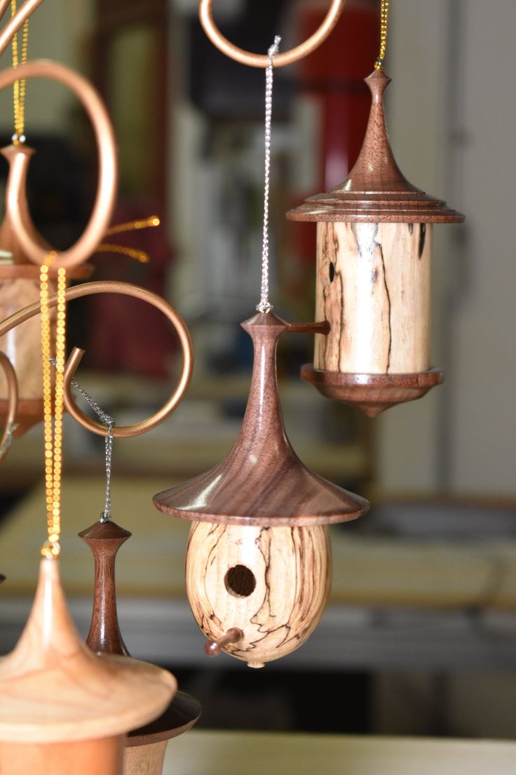 three wooden birdhouses hanging from chains on a table