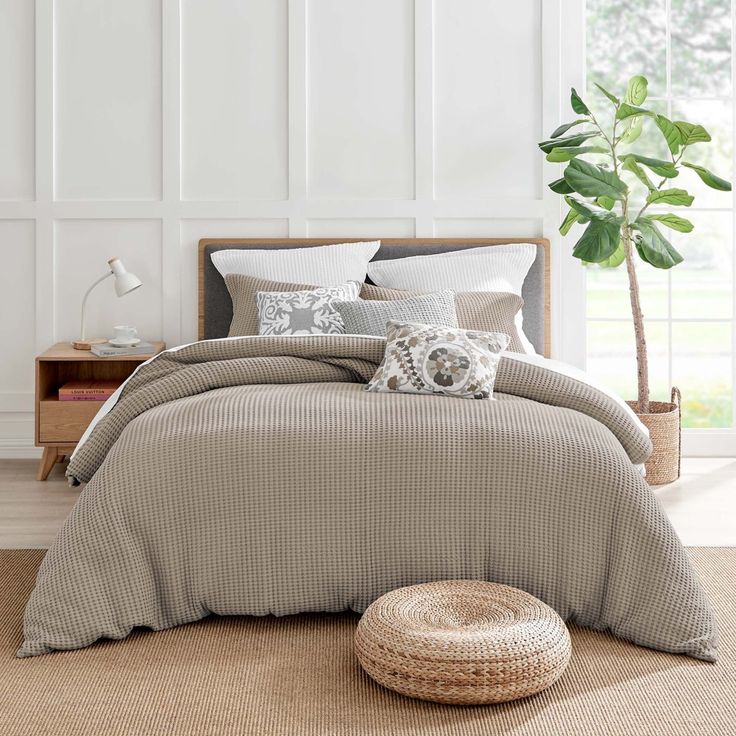 a bed in a room with white walls and a potted plant on the floor