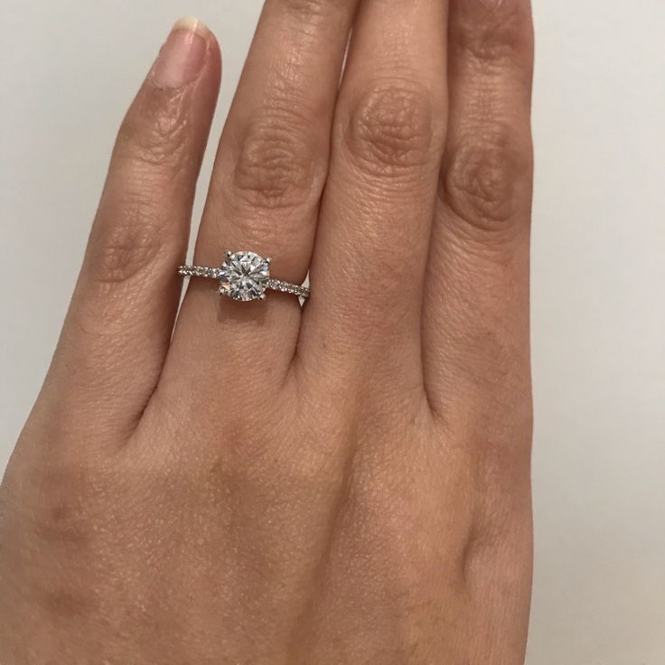 a woman's hand with a diamond ring on top of her finger and the other hand holding an engagement ring