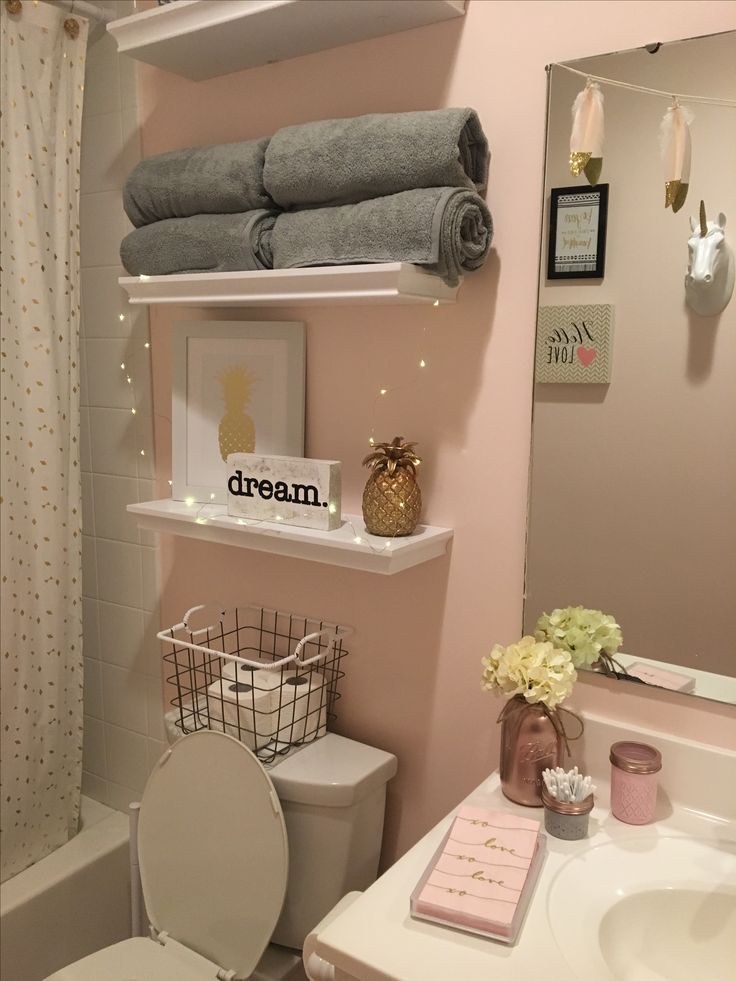 a bathroom with pink walls and shelving above the toilet