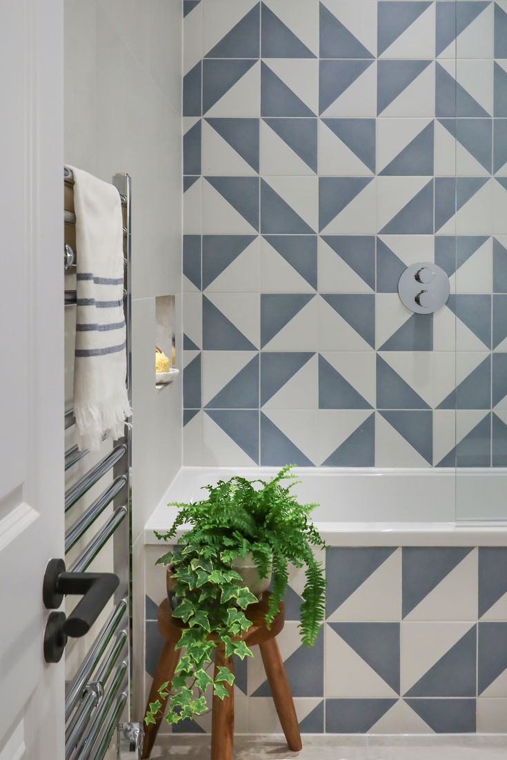 a potted plant sitting on top of a wooden stand next to a bath tub