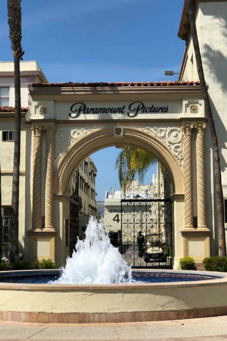 a fountain in front of a building with palm trees