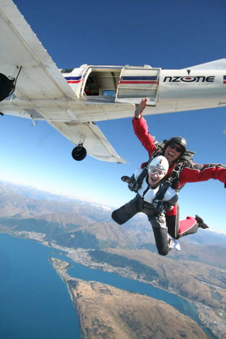 two people are in the air with parachutes attached to their feet and one person is wearing a helmet