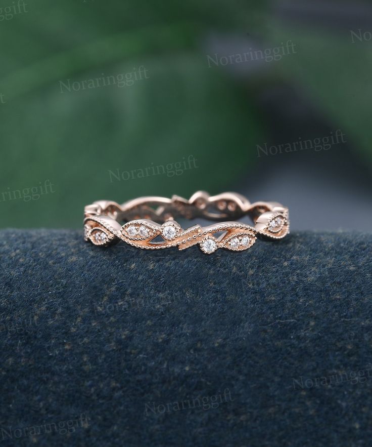 a rose gold wedding band with three diamonds on the top and bottom, sitting on a black surface