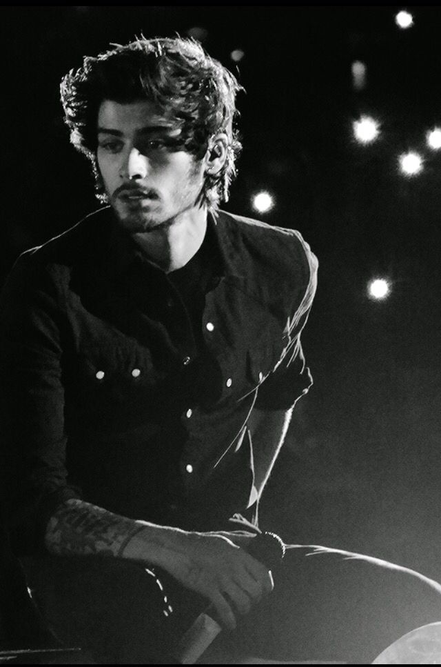 black and white photograph of a young man sitting on a stool in front of some lights