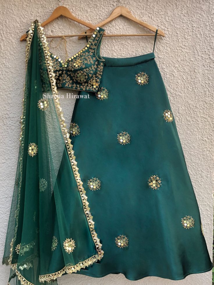 This emerald green blouse and lehenga in threadwork and sequins work embroidery is perfect for a mehendi or cocktail event.  It is teamed with a green net dupatta with gold border work and scattered butis. Semi-stitched Green Choli For Eid, Green Semi-stitched Lehenga With Dupatta, Semi-stitched Green Lehenga With Dupatta, Bollywood Style Green Art Silk Lehenga, Green Bollywood Art Silk Lehenga, Green Art Silk Lehenga With Zari Work, Green Art Silk Lehenga For Festive Occasions, Green Bollywood Choli In Dola Silk, Semi-stitched Green Choli For Navratri