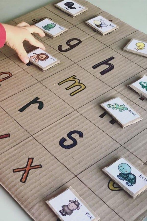 a child's hand is on top of a board game with letters and numbers