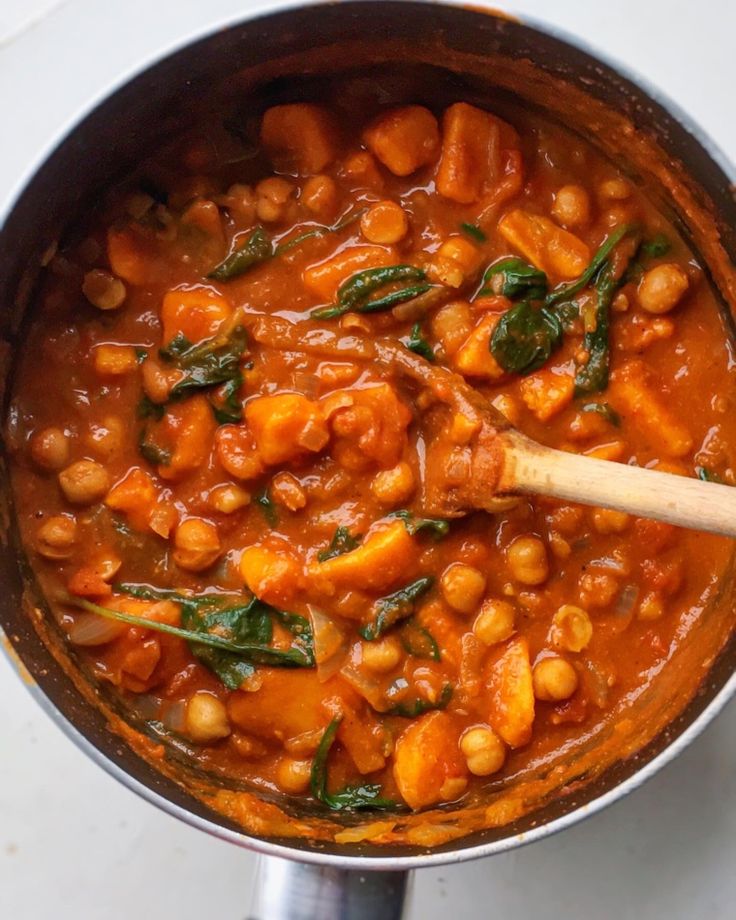 chickpeas and spinach stew in a pot with a wooden spoon on the side