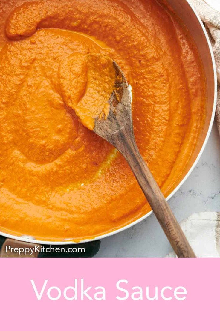 a bowl filled with orange sauce next to a wooden spoon