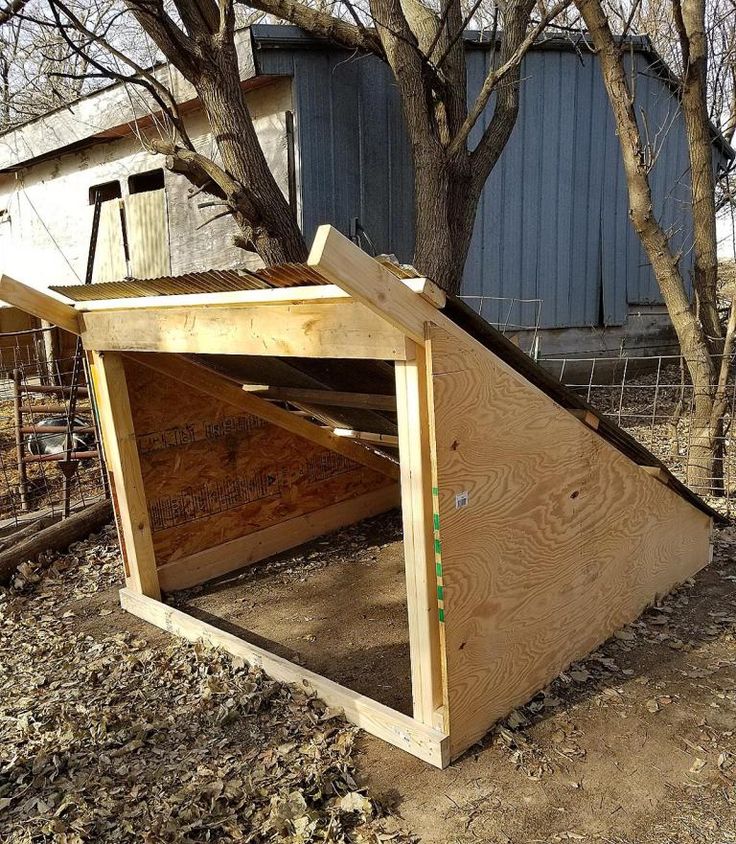 a wooden structure sitting in the middle of a yard next to a tree and fence