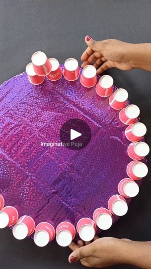 two hands holding a purple heart shaped table with pink cups on it and white candles in the middle