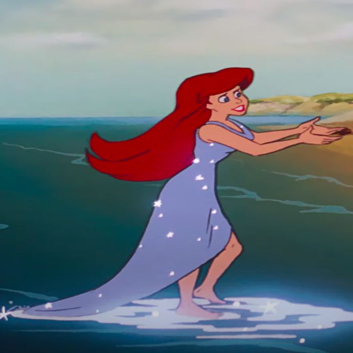 the little mermaid is standing in the water