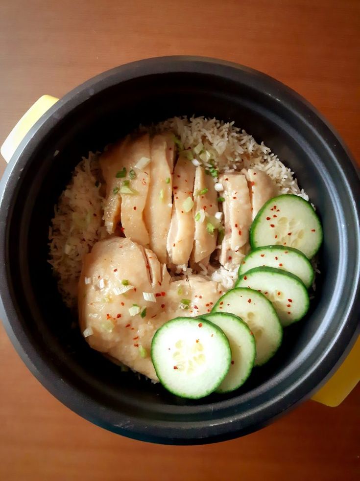 chicken rice with cucumbers in a black bowl