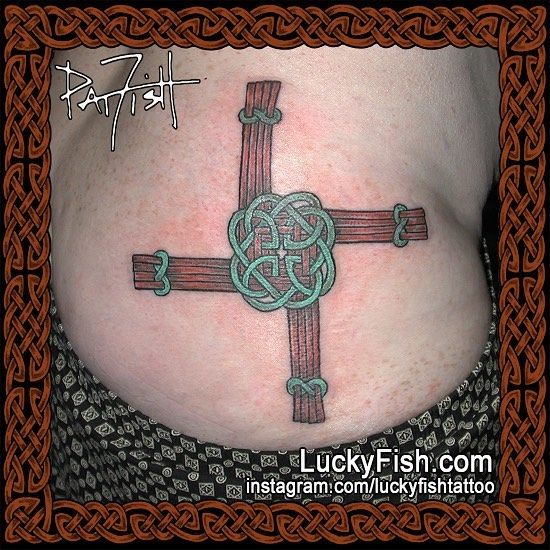 a woman's stomach with a celtic cross tattoo on it