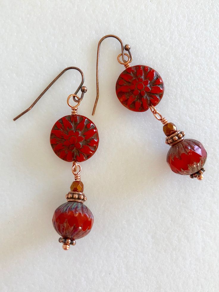 "Beautiful coral red Czech glass dahlia flowers with burnt orange silk Picasso Premium beads and copper accents. Premium Czech glass beads featuring 14 mm coral red pressed glass dahlia flower wire wrapped with 11 x 10 mm burnt orange silk Czech round with carved ends and rustic Picasso finish. Beads are accented with fire polished crystals and antique copper beaded spacers. They hang from copper French ear wires. Total drop is 2\". Perfect fall accessory!" Handmade Red Flower Earrings For Festive Occasions, Adjustable Red Flower Beaded Earrings, Festive Red Flower Earrings, Handmade Red Czech Glass Beaded Earrings, Artisan Red Copper Earrings, Adjustable Red Czech Glass Beaded Earrings, Handmade Red Flower Earrings With Round Beads, Handmade Red Flower Earrings, Artisan Red Czech Glass Jewelry