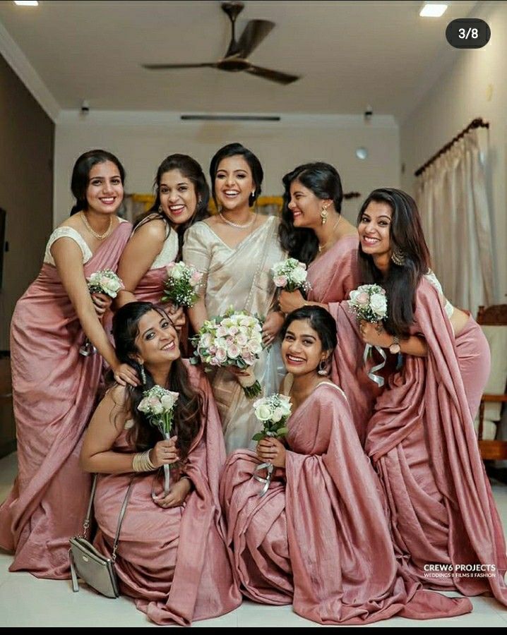 a group of women standing next to each other wearing pink dresses and holding bouquets