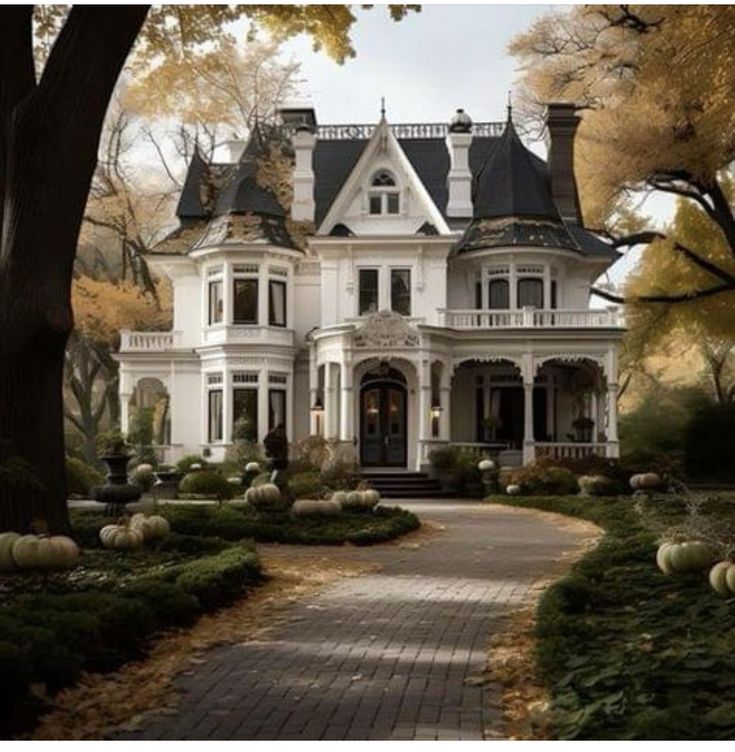 a large white house surrounded by trees and pumpkins