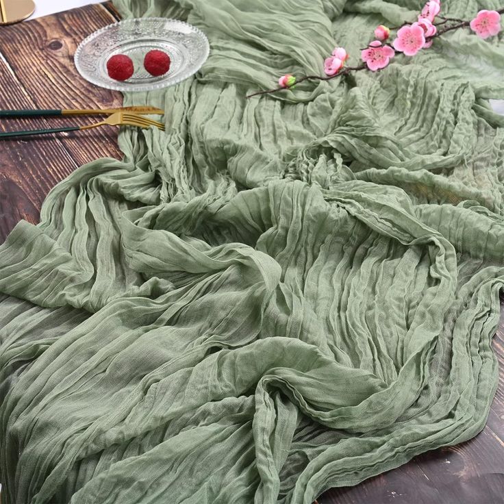 the table is covered with green cloths and pink flowers on it, along with other crafting supplies