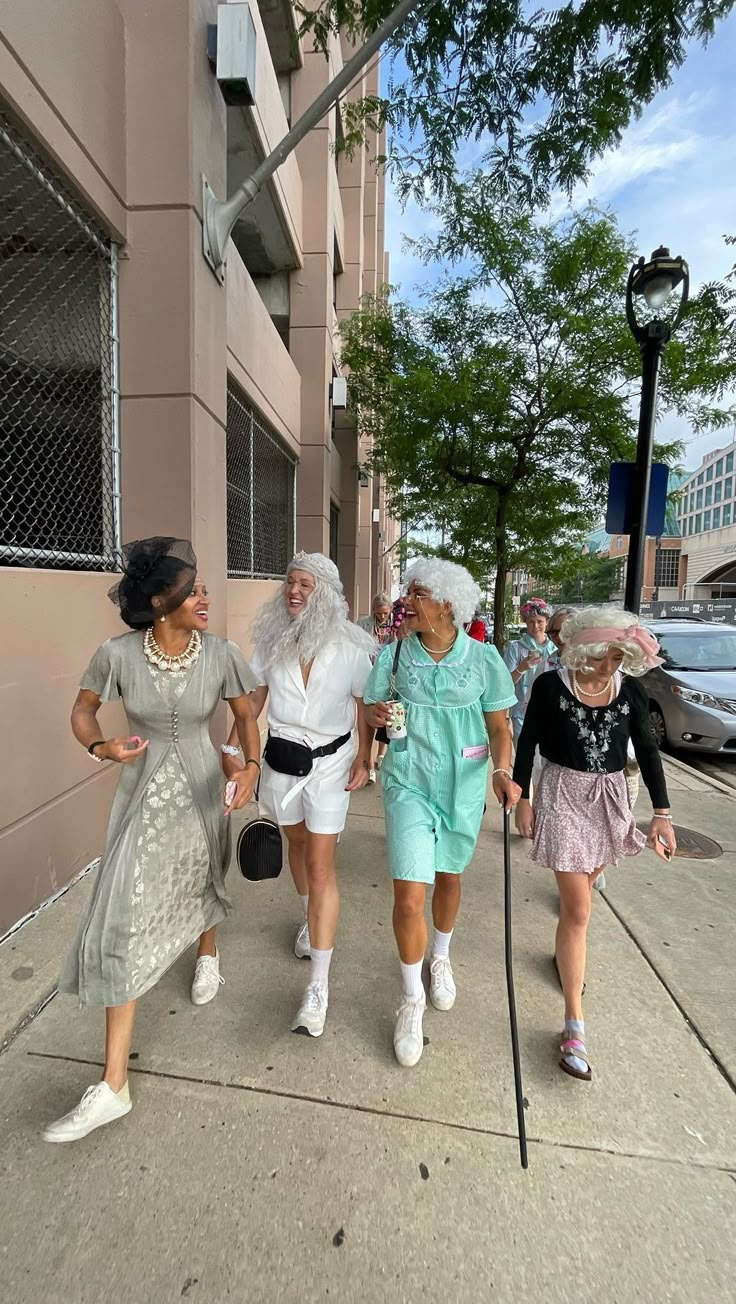 three older women walking down the sidewalk with one holding a cane and two wearing dresses