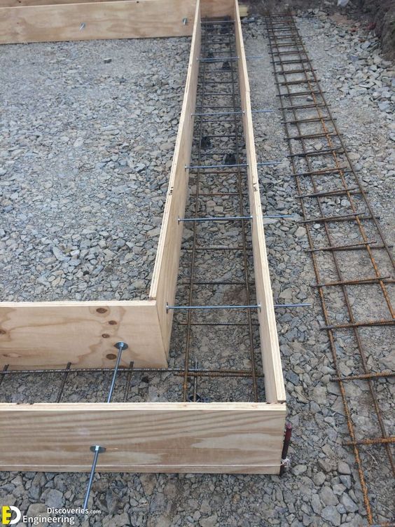 an unfinished bed frame sitting on top of some rocks and gravel with metal bars attached to the sides