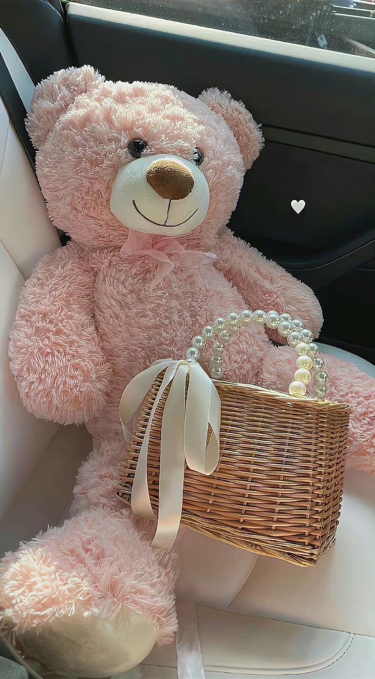 a pink teddy bear sitting in the back seat of a car with a wicker basket