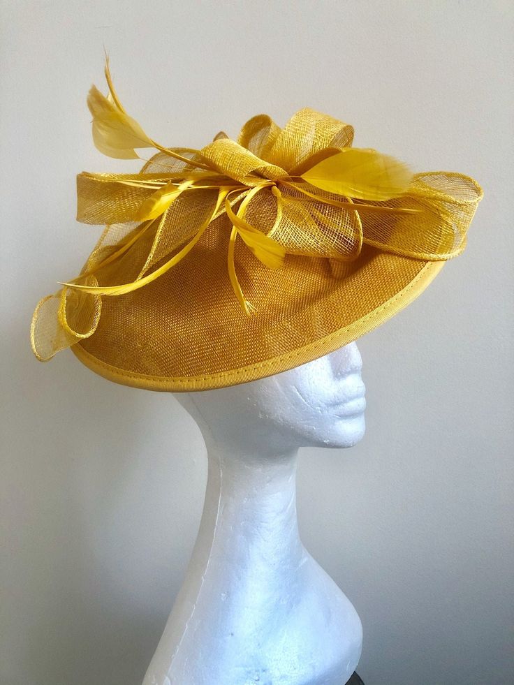 A striking sunshine yellow coloured fascinator, composed of a circular yellow Sinamay base adorned with loops of rich sunshine yellow Sinamay and finished with hand shaped feathers in the same glamorous shade. A striking addition to any formal outfit. Fascinator measuring approx 30cm in diameter. Please note as our fascinators are hand dyed to order if you feel this colour may not be quite right please request to see a colour chart. If you would like the fascinator created in an alternative dye colour which we don't currently stock there will be a charge of £30 to cover the cost of the dye and the labour.  Our timeless pieces are perfect for any special occasion from Weddings to The Kentucky Derby and Summer Garden Parties! We offer ready to wear pieces in a variety of styles and colour! H Yellow Mini Hats For Races At Royal Ascot, Yellow Mini Hat For Royal Ascot Races, Yellow Summer Fascinator For Races, Yellow Hat Fascinator For Garden Party, Yellow Short Brim Fascinator For Church, Spring Yellow Fascinator Hat, Spring Yellow Fascinator With Curved Brim, Yellow Fascinator Hat For Garden Party, Yellow Church Fascinator With Short Brim