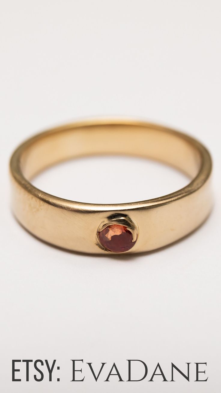 a gold ring with a red stone in the middle