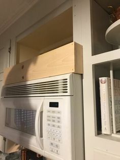 a microwave oven sitting on top of a wooden shelf next to a bookcase with books