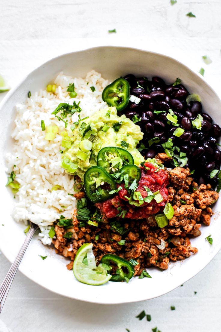 a white bowl filled with rice, beans and vegetables