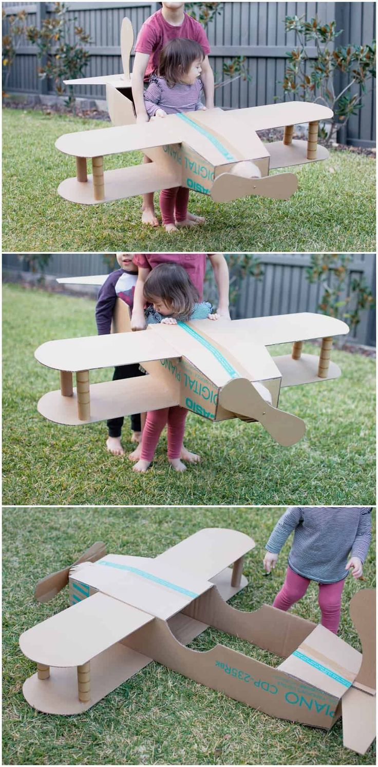 two girls are playing with cardboard airplanes in the yard, and one girl is trying to make