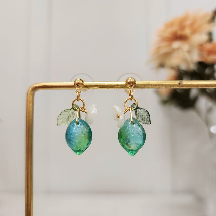 Our cute lime earrings are made with glass lime, acrylic leaf, acrylic flower and 14k gold plated studs/hooks which are good for delicate ears. We have 925 sterling silver plated version available, please contact seller for detail.Size: the stud style(W x L): 0.5" x 1.1" the hook style(W x L): 0.5" x 1.5" Elegant Green Resin Earrings, Elegant Green Resin Jewelry, Cute Green Jewelry For Party, Green Drop Flower Earrings, Green Flower Drop Earrings, Trendy Leaf-shaped Earrings For Gifts, Green Leaf-shaped Party Jewelry, Green Resin Earrings For Summer, Summer Gold Resin Earrings