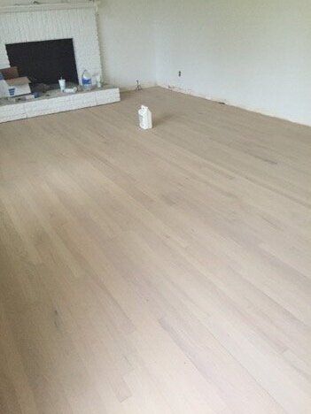 an empty living room with hard wood flooring and a fire place in the corner