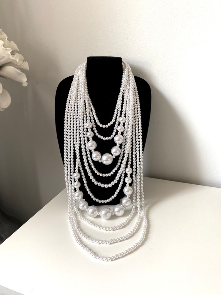 "Big bold white multi strand long layered acrylic pearl necklace. Stunning Unique 10 layers of different size acrylic pearls make this necklace truly showstoppers. There's nothing like pearls to feel your most classic and feminine,  Perfect piece to complement your style. Approximate length: 20\" + 4\" L (51cm+10cm) Drop 25\"(64 cm) Comes with earrings If you have any question please contact me I am inviting you to explore and enjoy my jewelry store; perhaps you will discover something unique for yourself or as a gift for someone special in your life. Thank you! https://www.etsy.com/shop/BravaFashionJewelry" Multi-strand Layered Pearl Necklace For Party, Multi-strand Layered Pearl Chain Necklace For Parties, Elegant White Multi-strand Long Necklace, White Multi-strand Layered Pearl Necklace, White Multi-strand Layered Necklace With Pearl Chain, White Multi-strand Pearl Chain Necklace, Elegant Layered White Jewelry, White Multi-strand Pearl Beaded Necklaces, White Elegant Multi-strand Layered Necklace