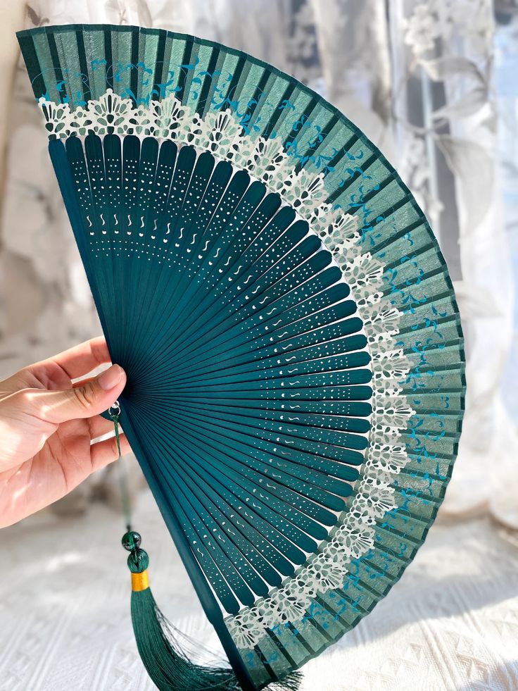 a hand holding a blue fan with white lace