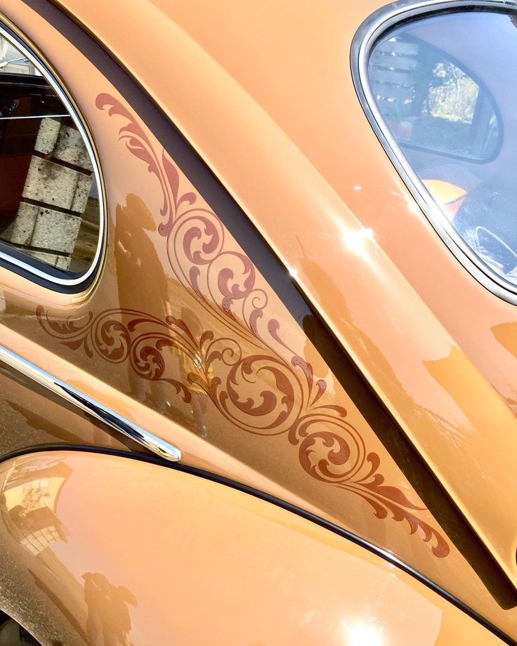 an orange car with ornate designs on it's side window and the passenger door