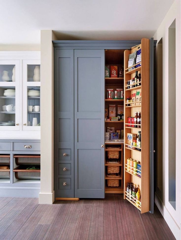 an open pantry door in the middle of a room with shelves and drawers on both sides